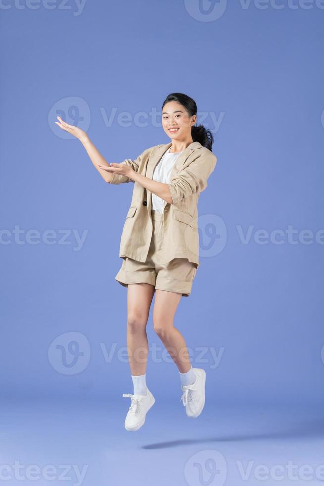 young happy positive smiling woman jump with hands showing nothing on lilac color background photo