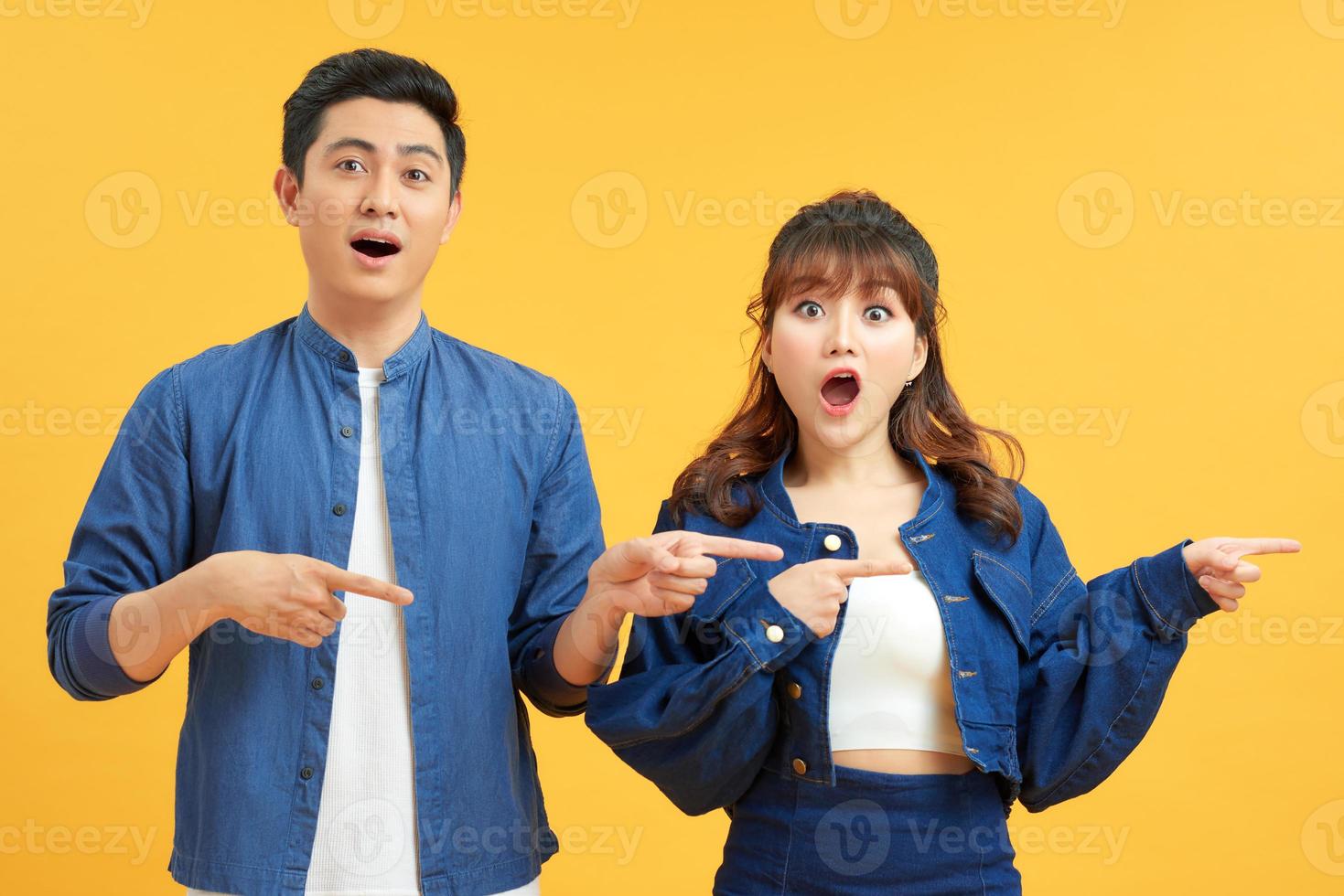 Beautiful young asian couple over white isolated background cheerful with a smile of face pointing with hand and finger up to the side with happy and natural expression on face photo
