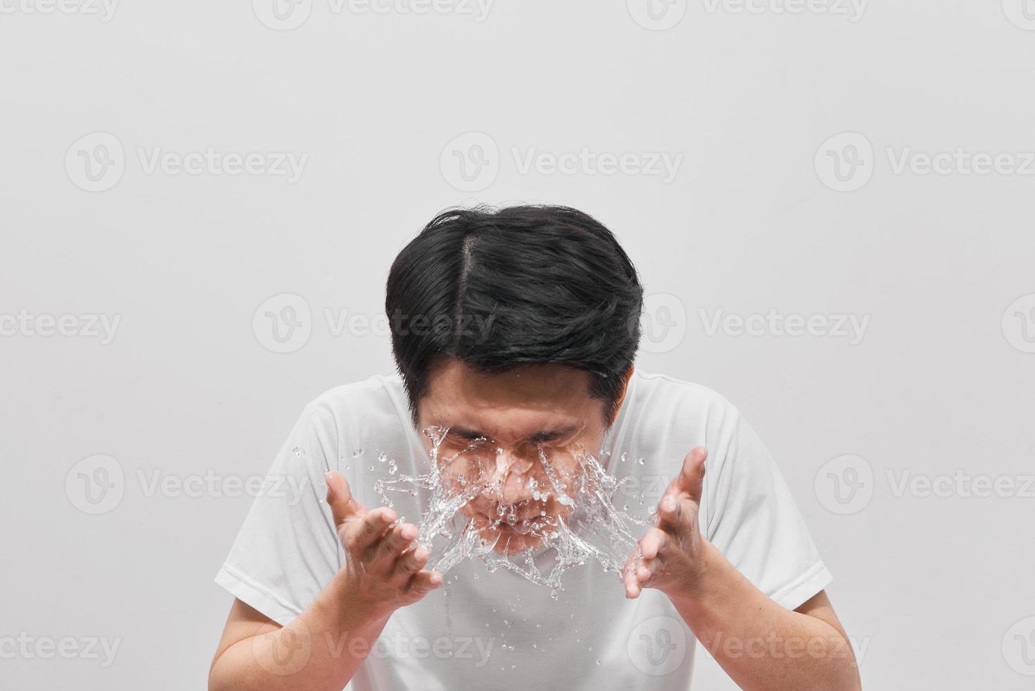 un hombre guapo se está lavando, salpicando agua, con fondo blanco foto