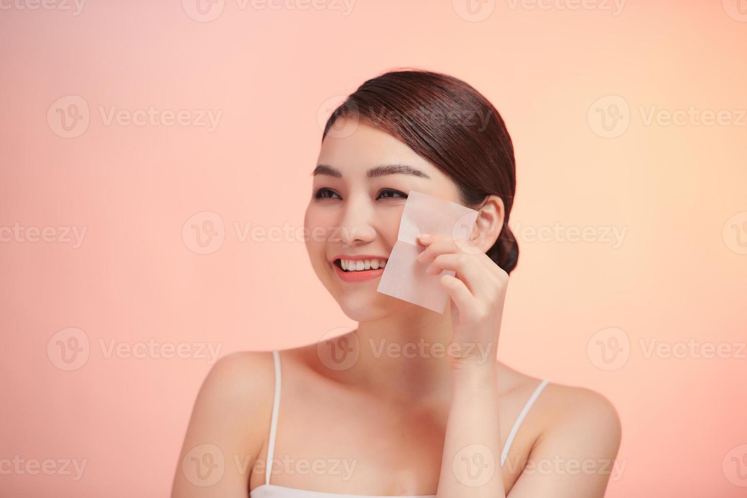Smiling woman using facial oil blotting paper portrait. photo