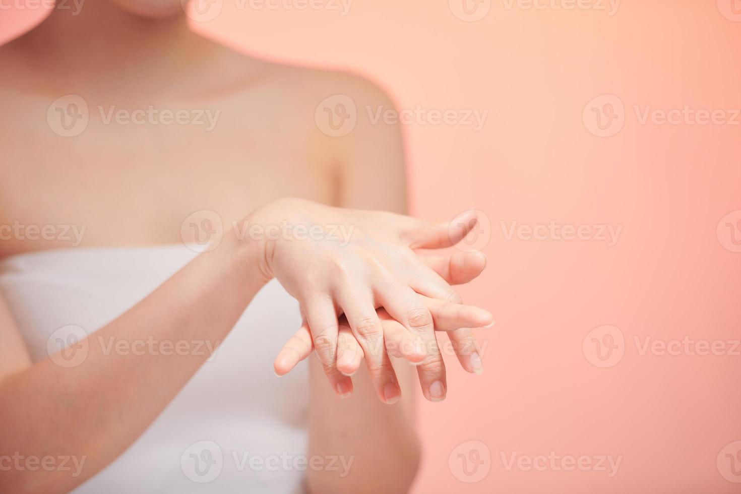 Beautiful young woman applying cosmetic moisturizer on hands photo
