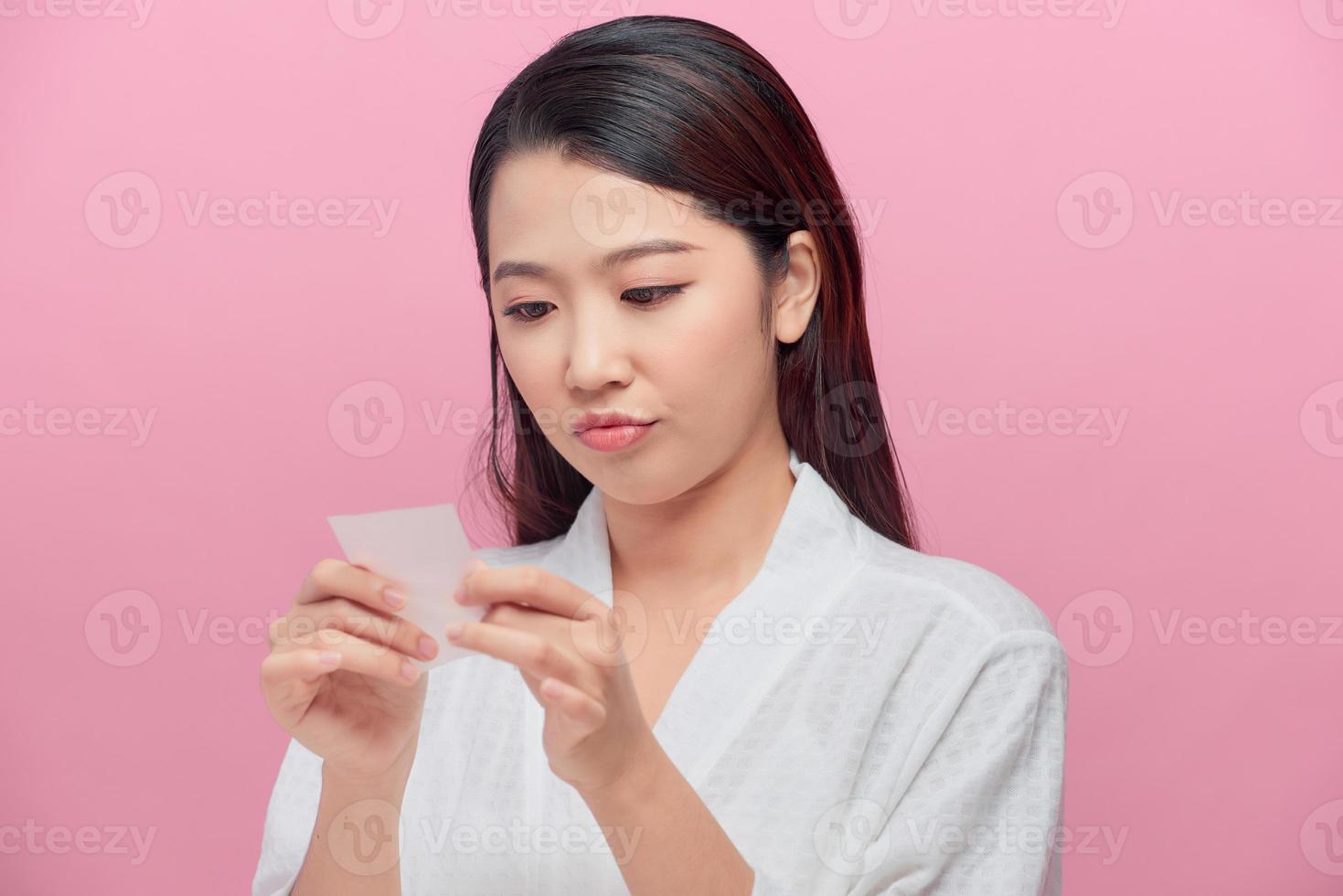Young asian skin care woman upset after use oil blotting paper on her face photo
