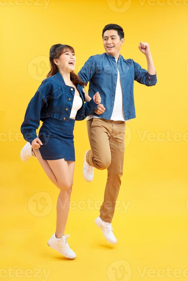Full length body size view of nice attractive lovely cheerful cheery couple jumping up in air isolated over yellow background photo