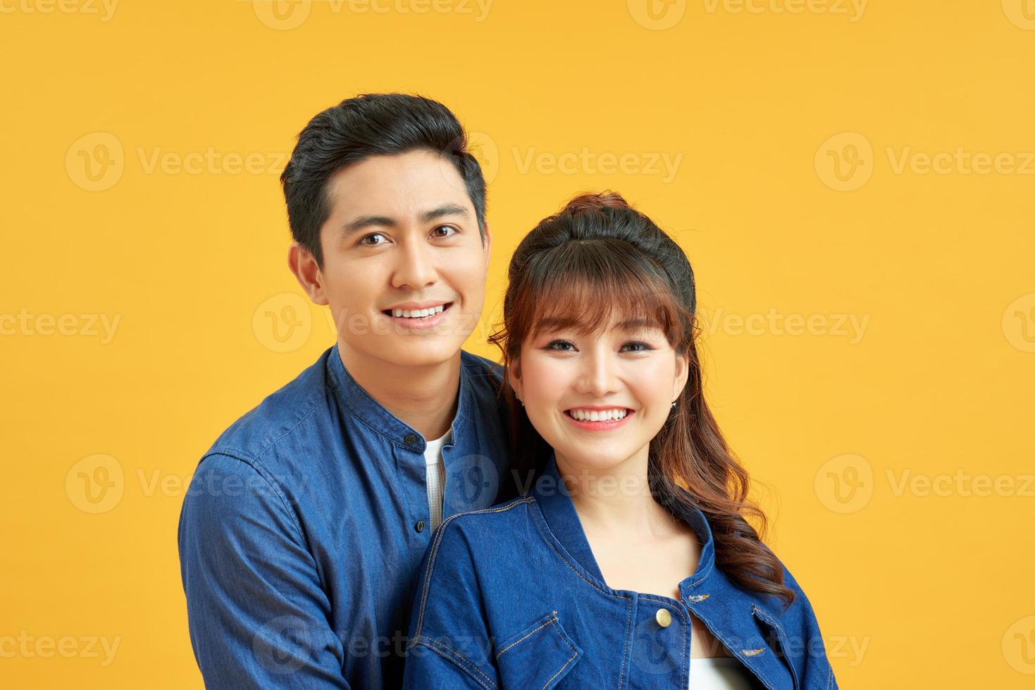 Excited cheerful young couple standing isolated over yellow background photo