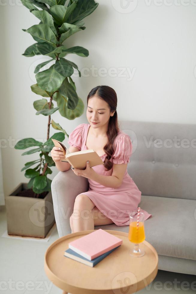 leisure, literature and people concept - smiling Asian woman reading book at home photo