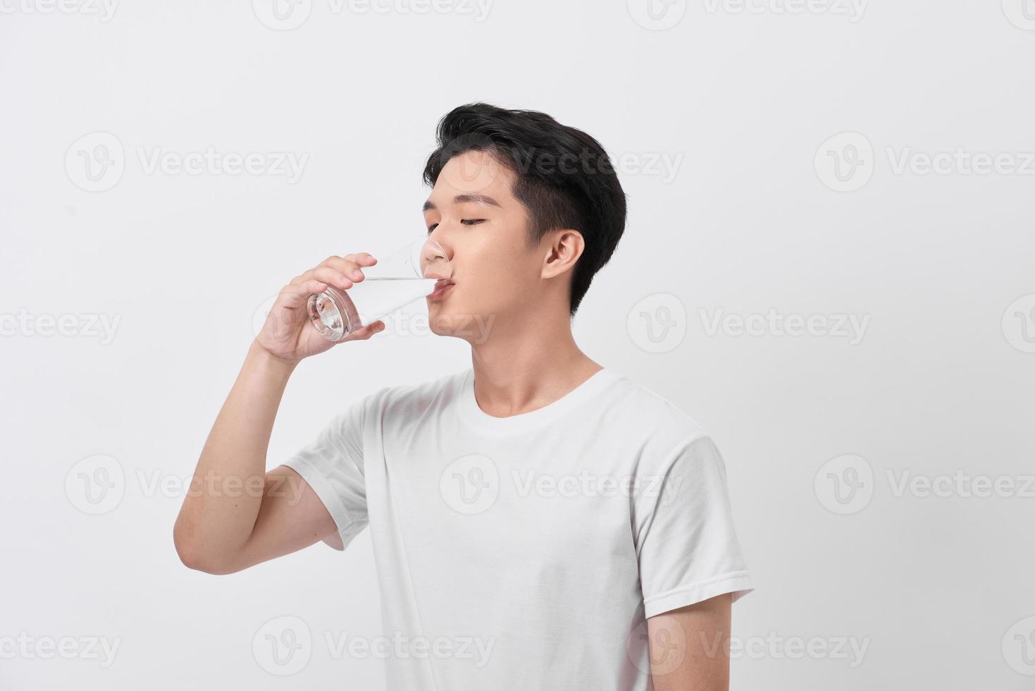Healthy and happy young man drinking water while relaxing at home photo
