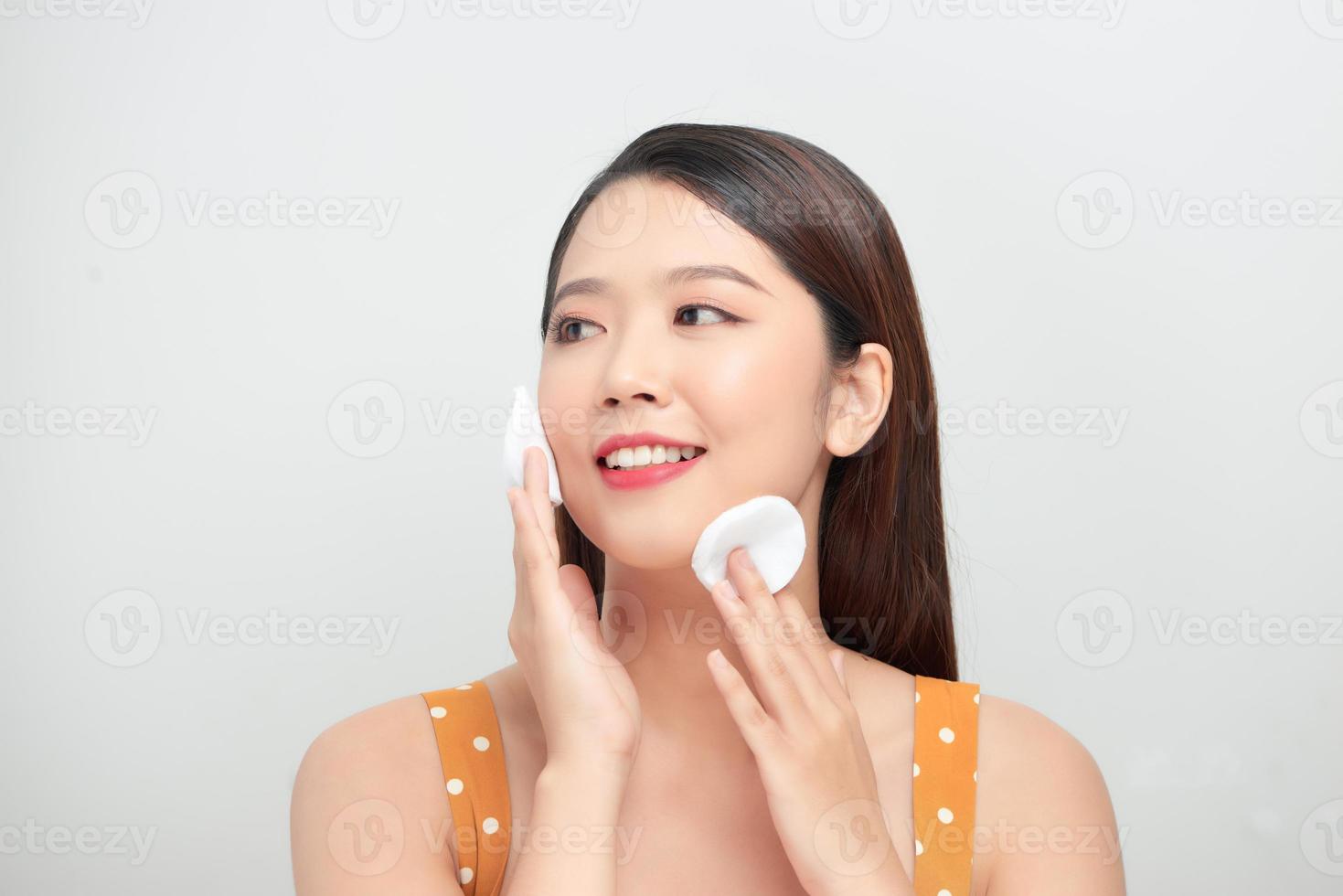Healthy fresh girl removing makeup from her face with cotton pad