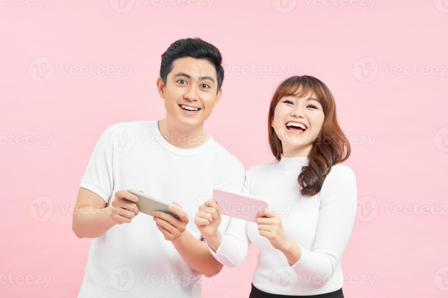 imagen de un hombre y una mujer curiosos frunciendo el ceño y mirando los teléfonos celulares de los demás, aislados sobre un fondo rosado. foto