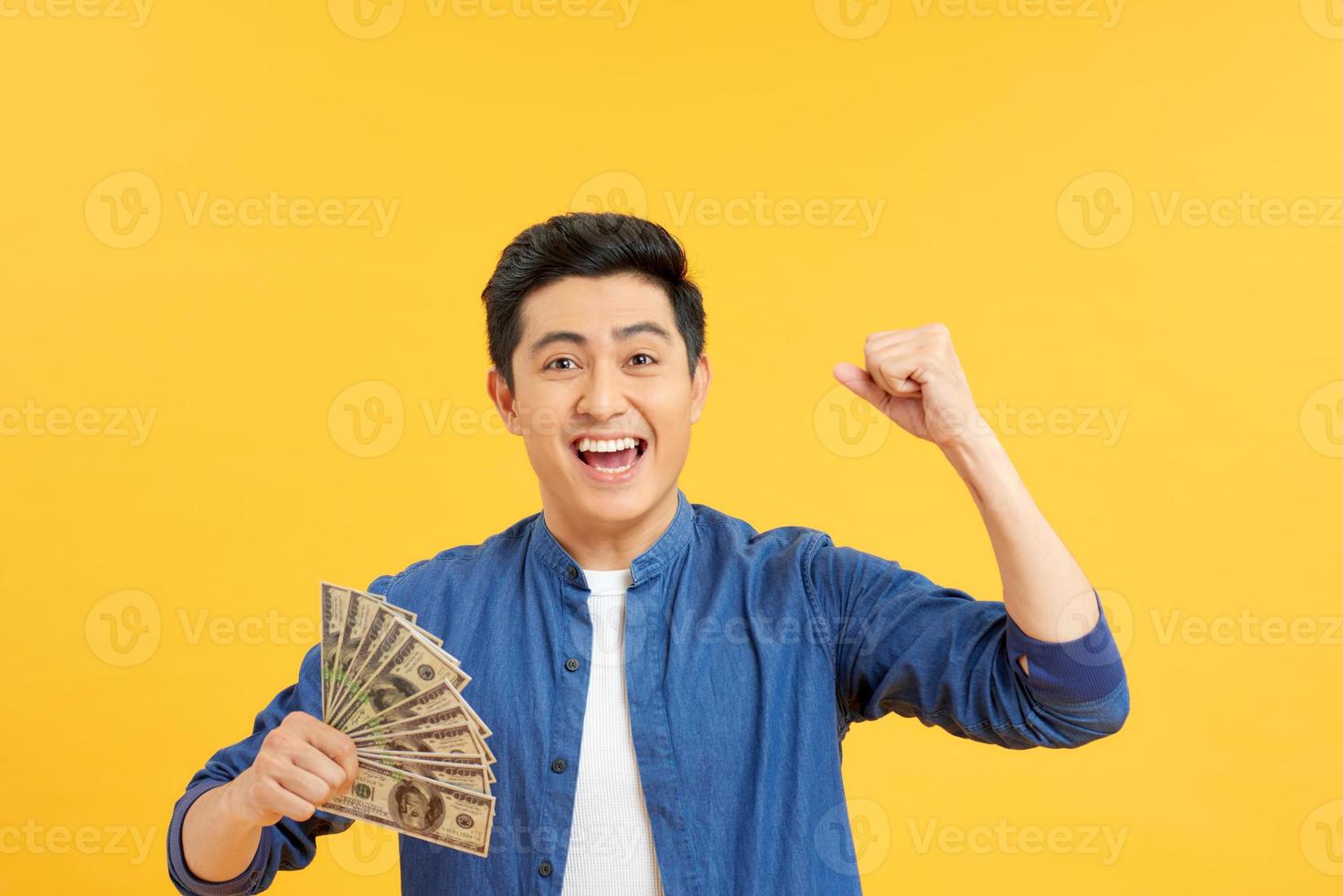 Closeup portrait, happy, excited successful senior lucky elderly man holding money dollar bills in hand isolated yellow background. Positive emotion facial expression feeling. Financial reward savings photo