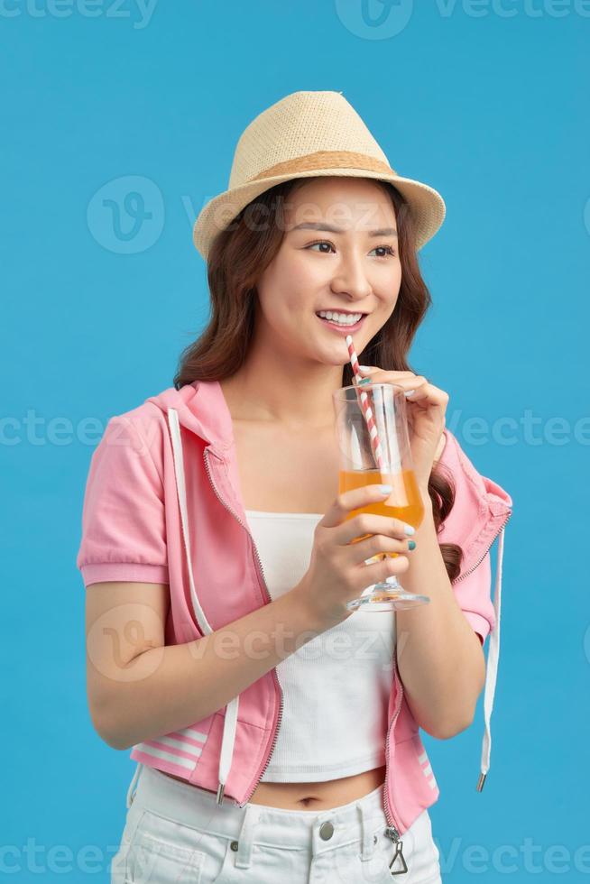 mujer joven feliz bebiendo jugo en un fondo azul foto