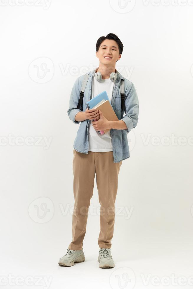 Smiling teenager with a schoolbag standing on wall background photo