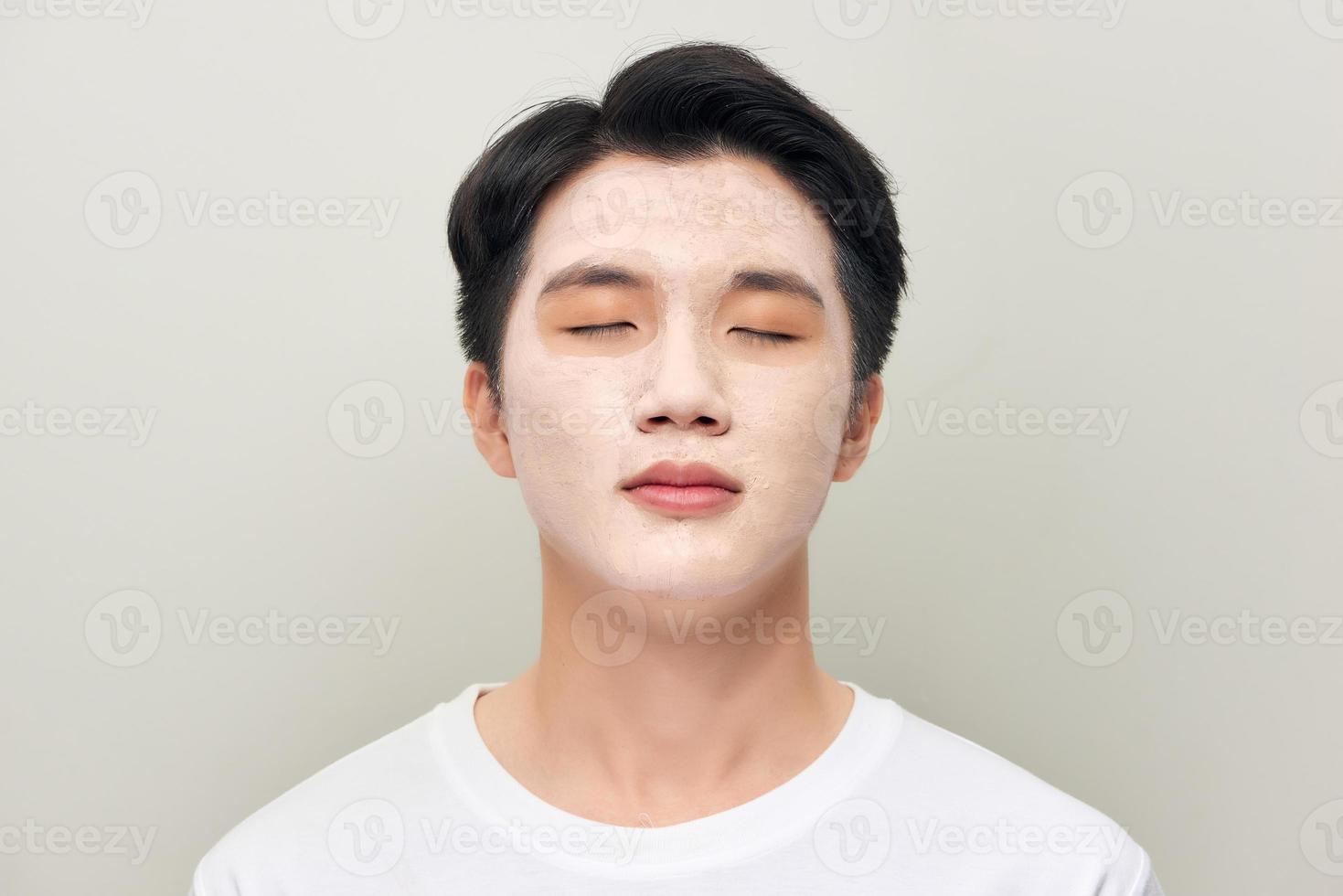 Front portrait of a white male wearing a mud mask beauty treatment. photo