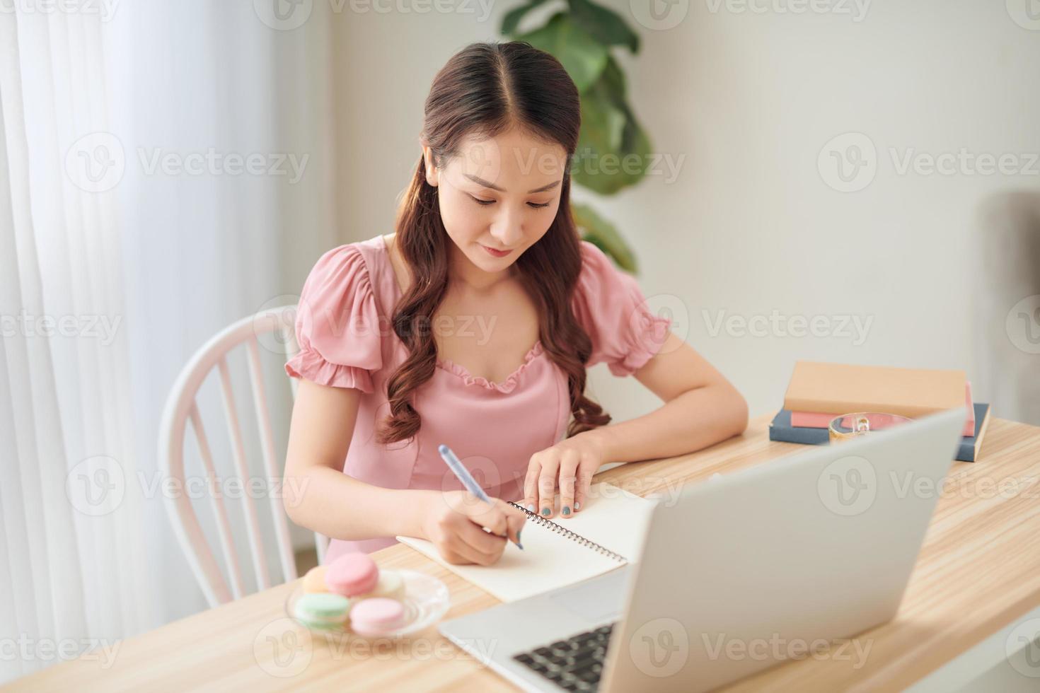 Attractive young woman working with laptop computer and documents while sitting at home, apartment photo