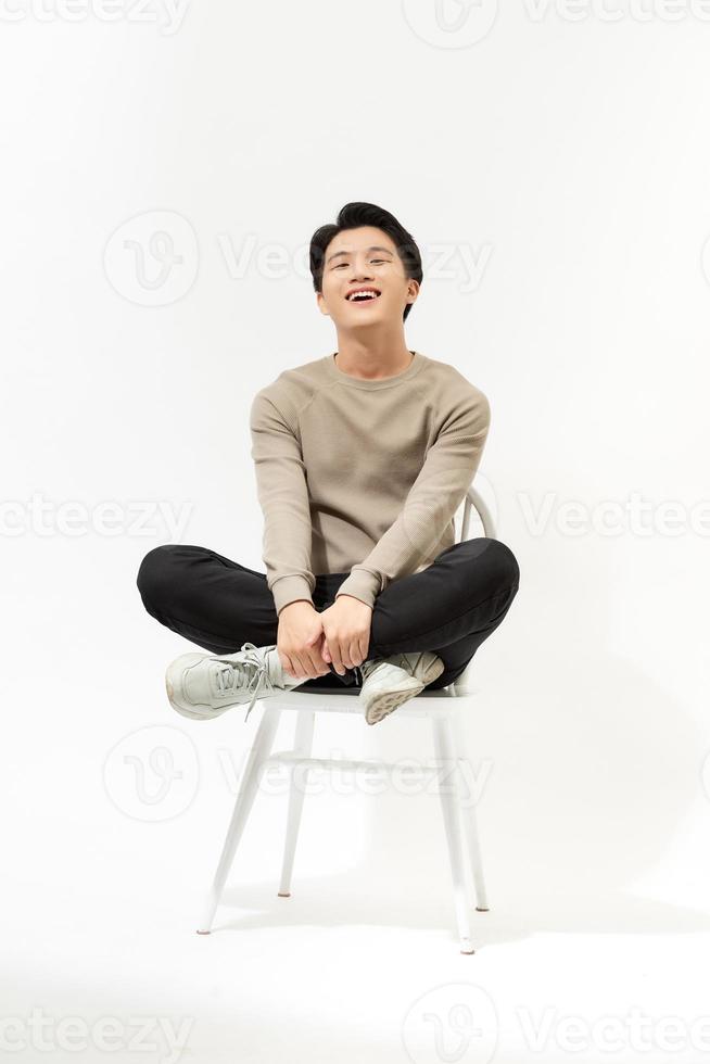 A portrait of happy asian man sitting on a chair over white background photo