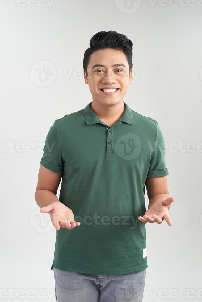 atractivo hombre casual de pie mientras usa jeans azules y camiseta verde sobre fondo blanco foto