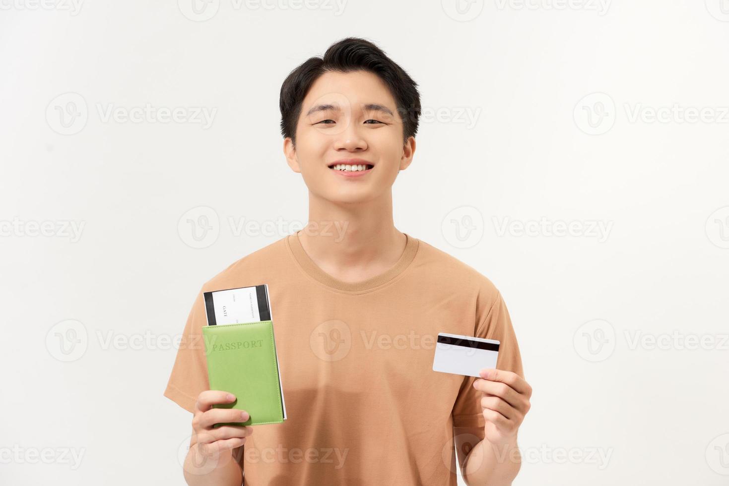 Portrait of a happy young man holding passport with tickets and showing plastic credit card isolated photo