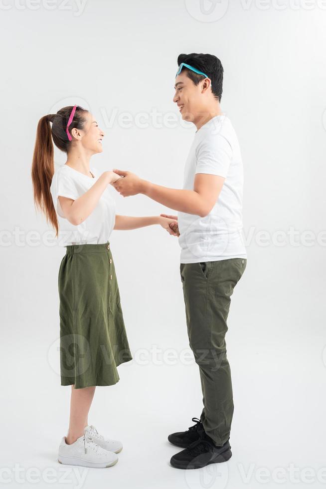 pareja sonriente bailando y tomándose de la mano, aislada en blanco foto