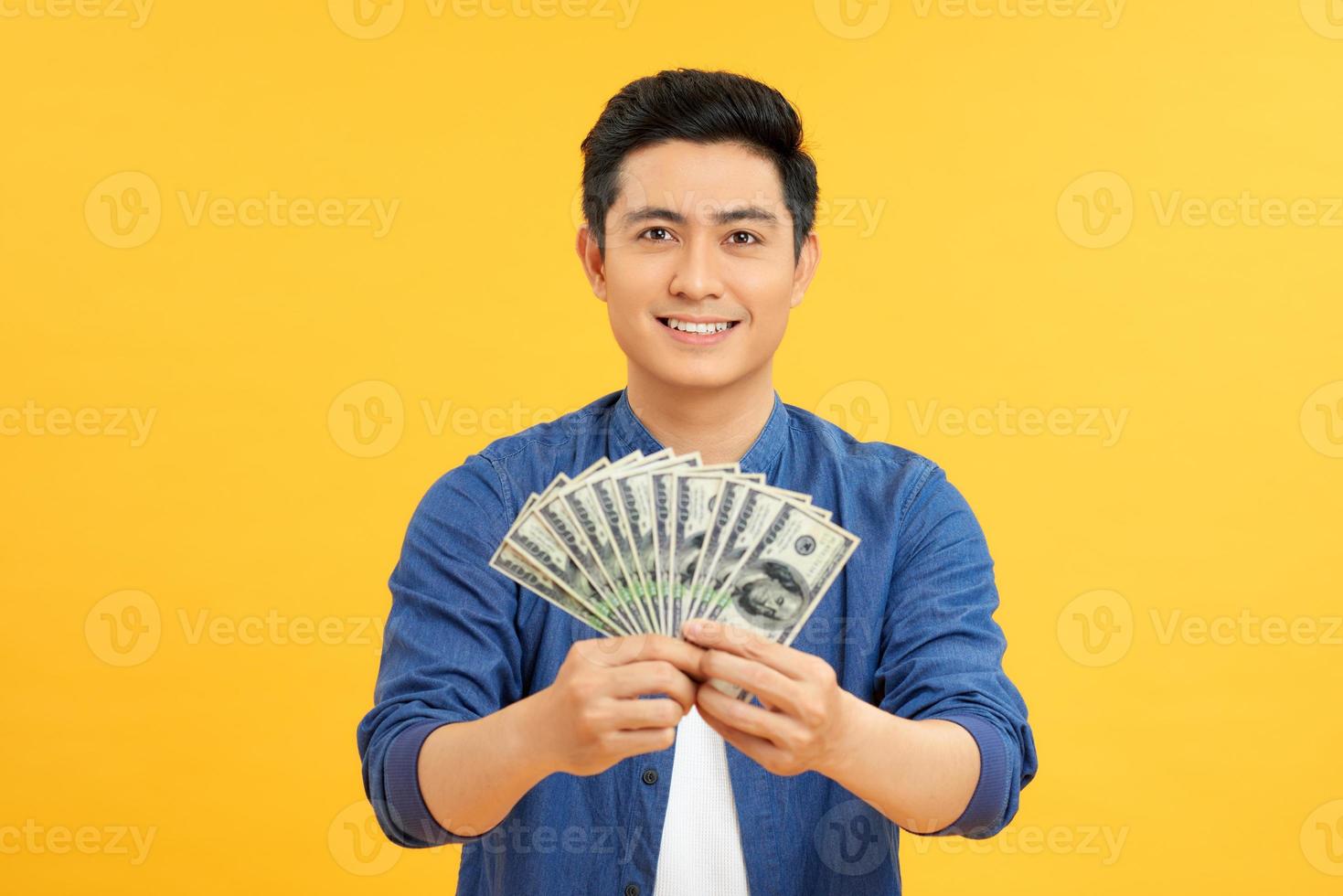 Astonished asian man holding bunches of dollars, lucky lottery winner photo