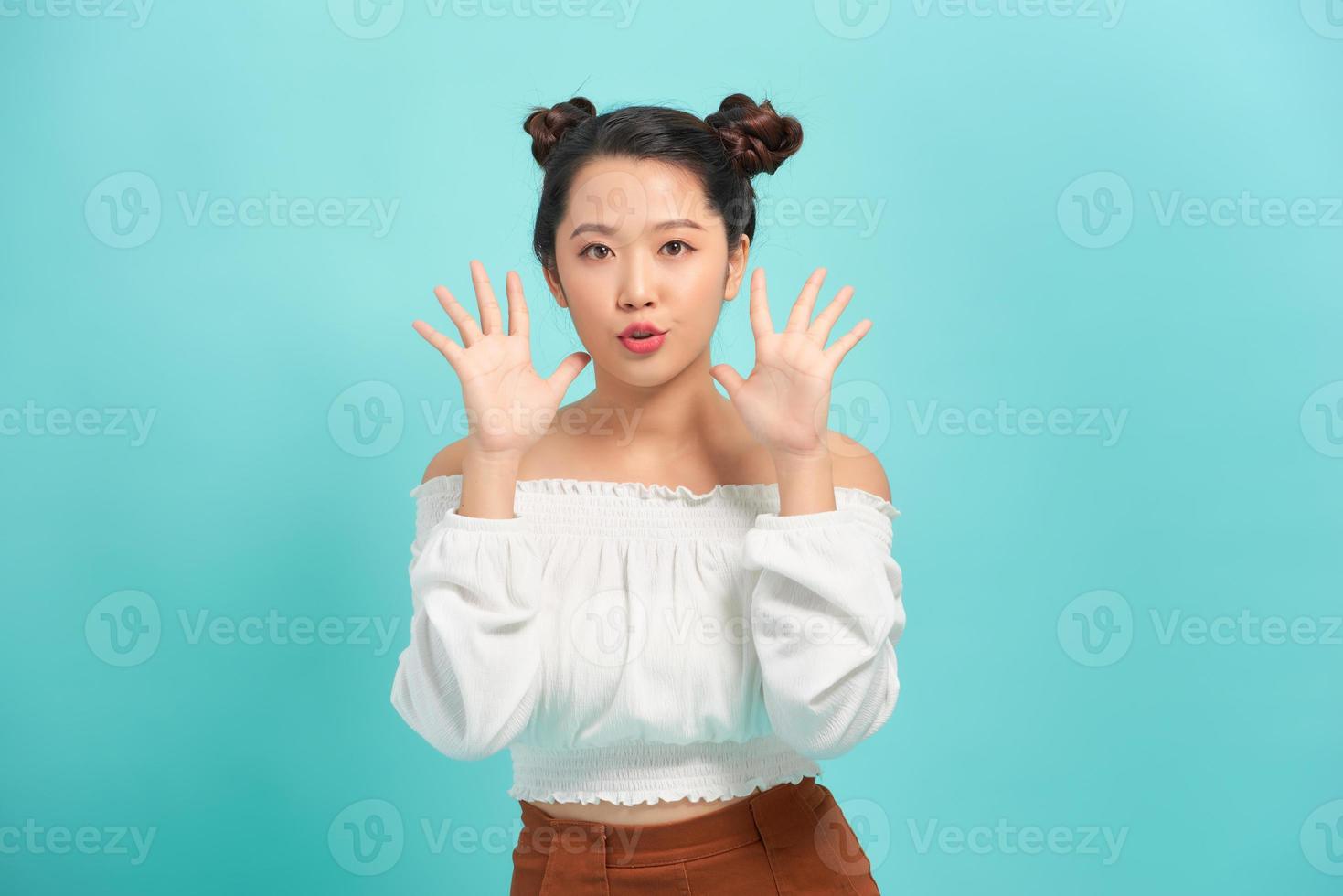 Expression of surprise and happiness. Emotional teen girl with open mouth spreads hands isolated on turquoise background photo