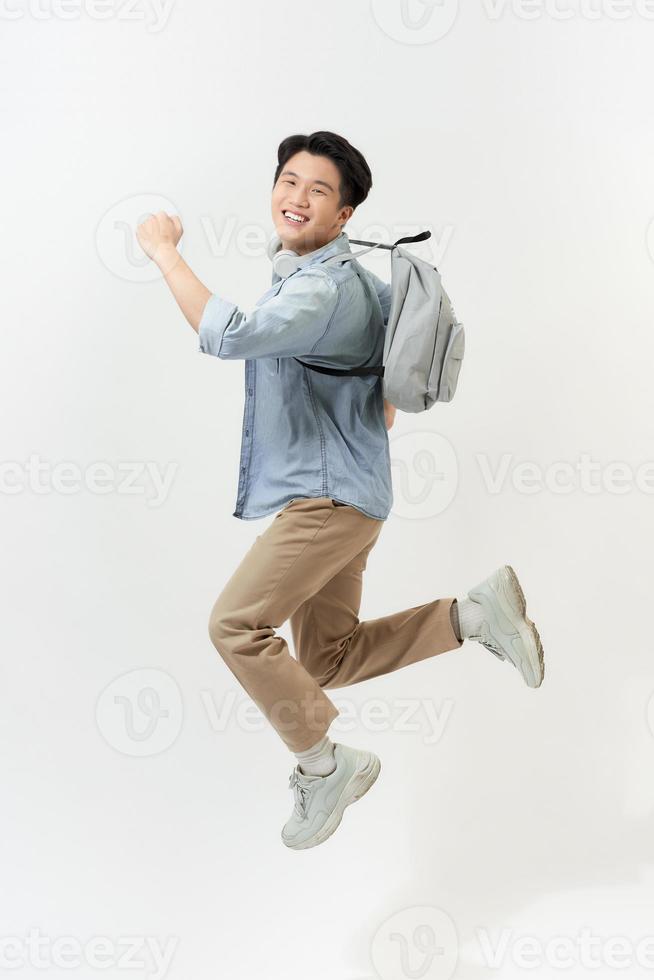 Full length portrait of a funny cheerful male student jumping on white background photo
