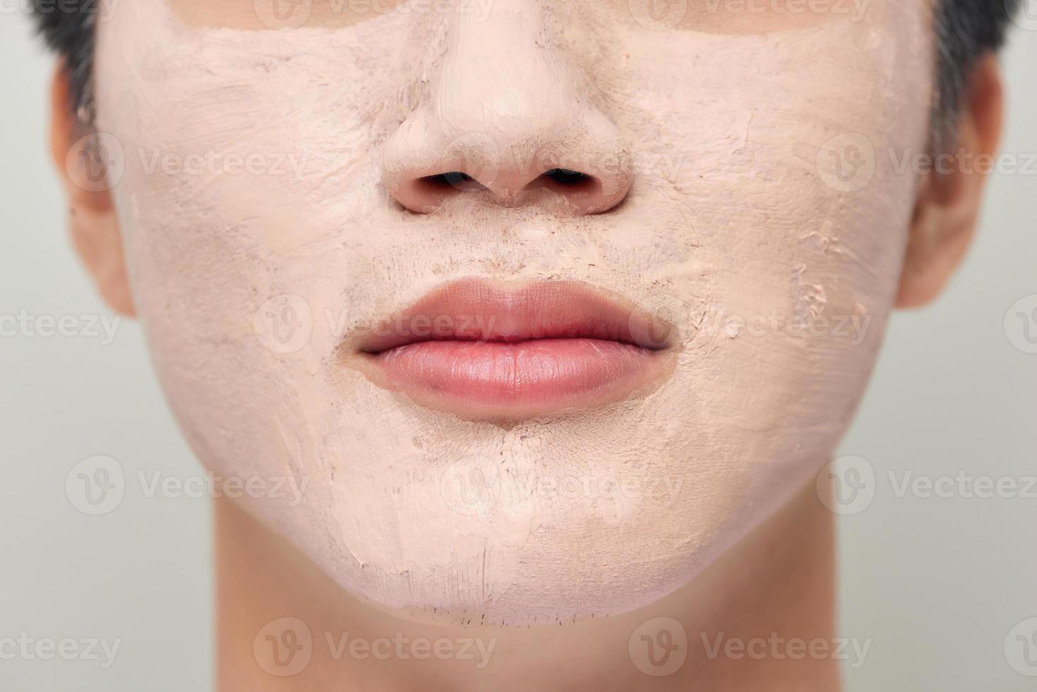 Handsome man with clay mask on his face against white background photo