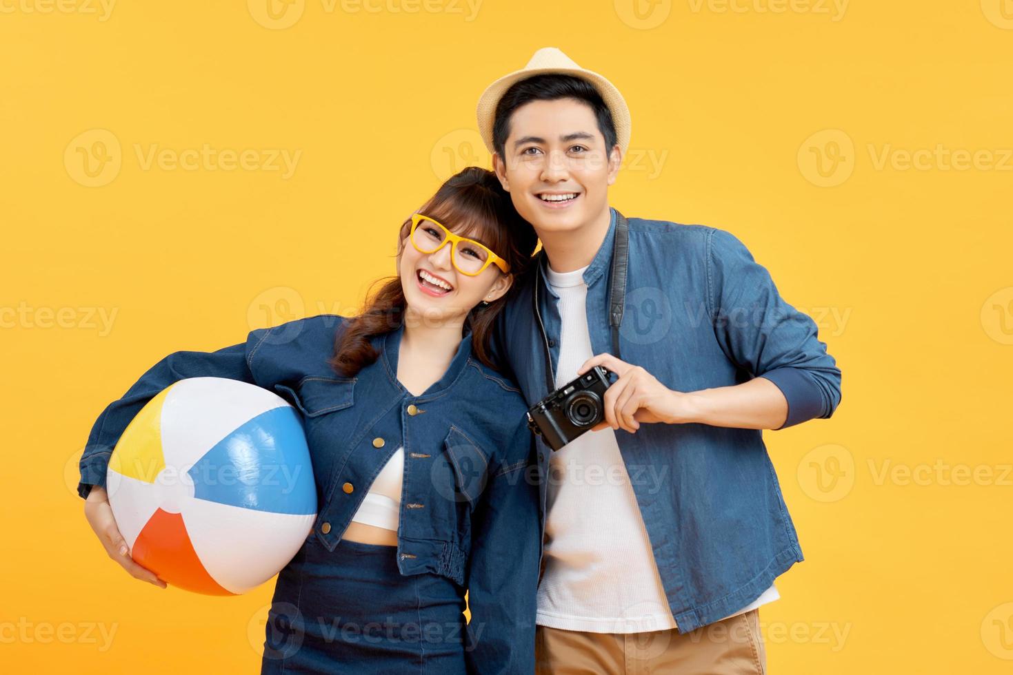 Lovely Asian couple in summer casual clothes with beach accessories isolated on colorful yellow banner background with copy space photo