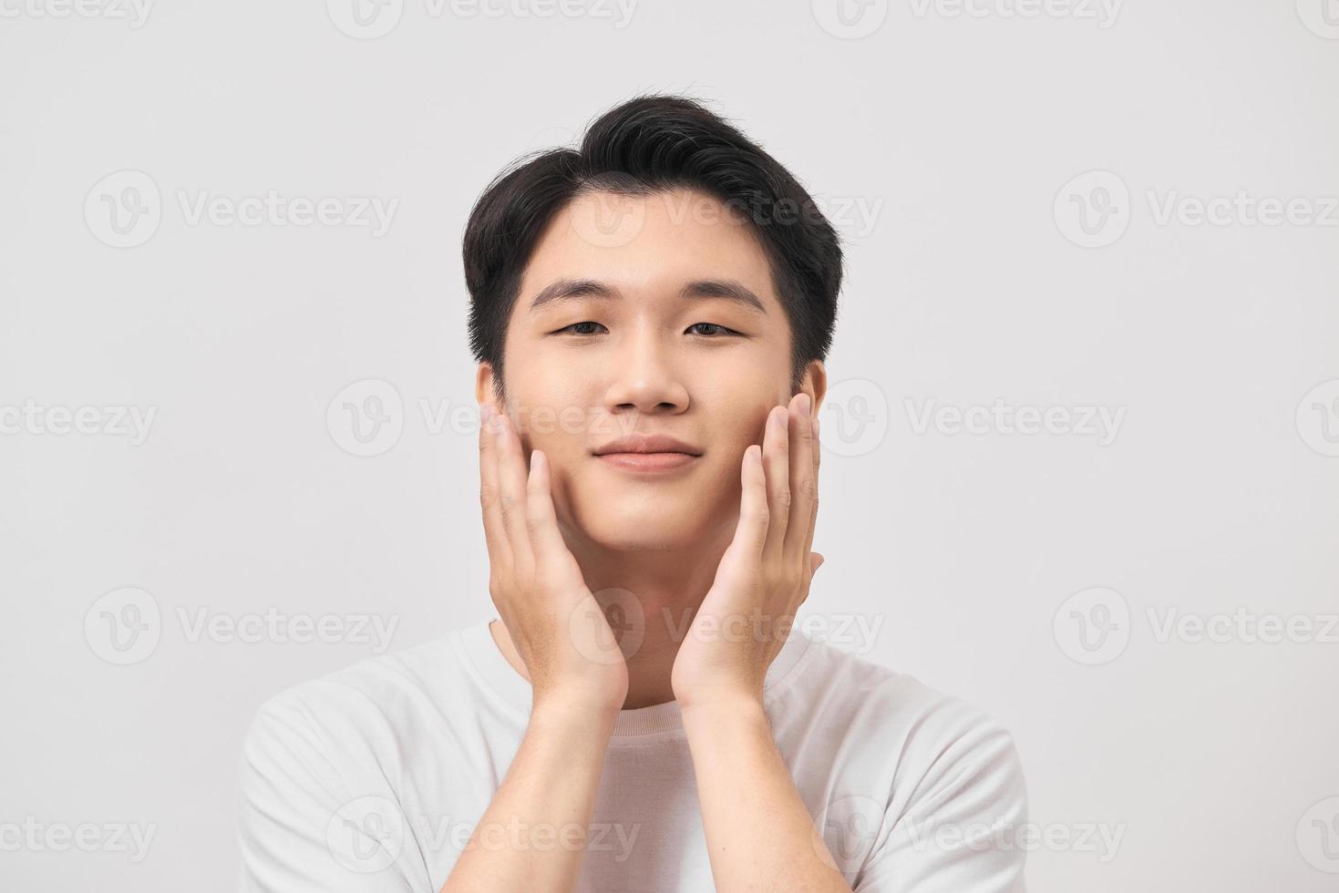 feliz y asombrado joven asiático tocándose la cara, impactado con una promoción inesperada de fondo blanco foto