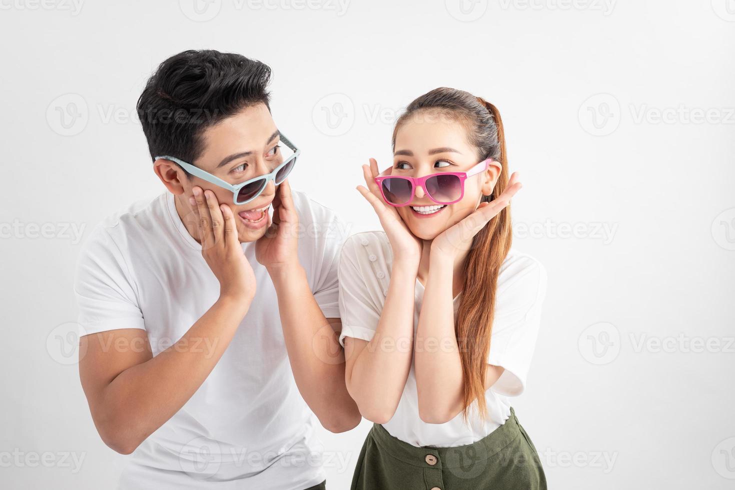 Gesture and people concept - Portrait of happy couple in sunglasses and white t-shirts, touches cheeks with both hands over white background photo