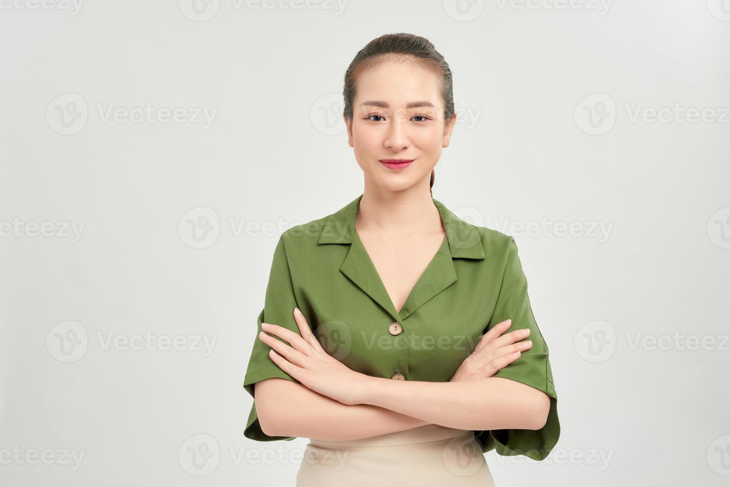 Portrait of a smiling asian businesswoman standing with arms folded and looking at camera isolated over white background photo