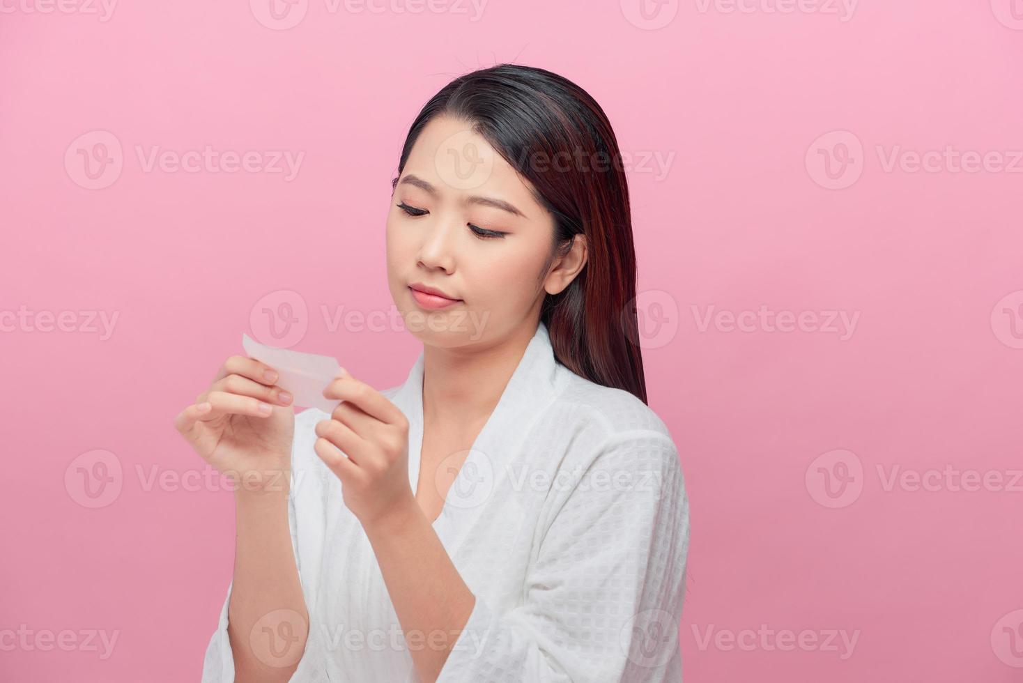 Closeup of beautiful asian girl model with natural face makeup looking at oil absorbing tissue photo
