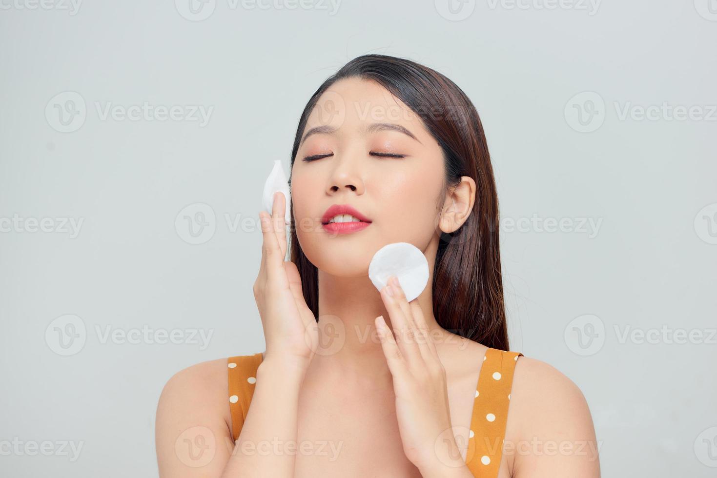 Beautiful woman cleaning face by cotton pad photo