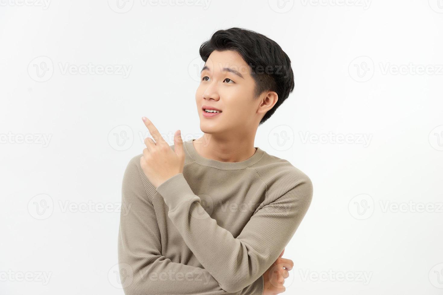 retrato aislado de un hombre asiático feliz y sonriente señalando con la mano un espacio vacío a un lado del fondo blanco de la foto de estudio