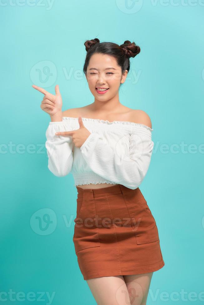 Young woman over isolated blue background pointing finger to the side photo