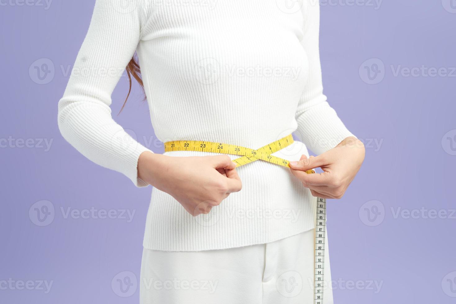 Cropped shot of a young woman measuring her waist photo