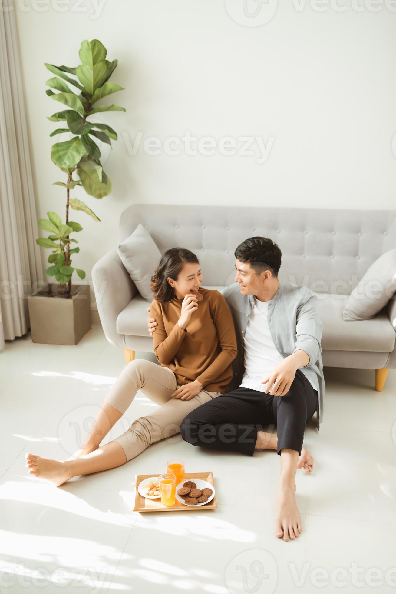 Couple sit on living room floor together eating 11137095 Stock Photo at