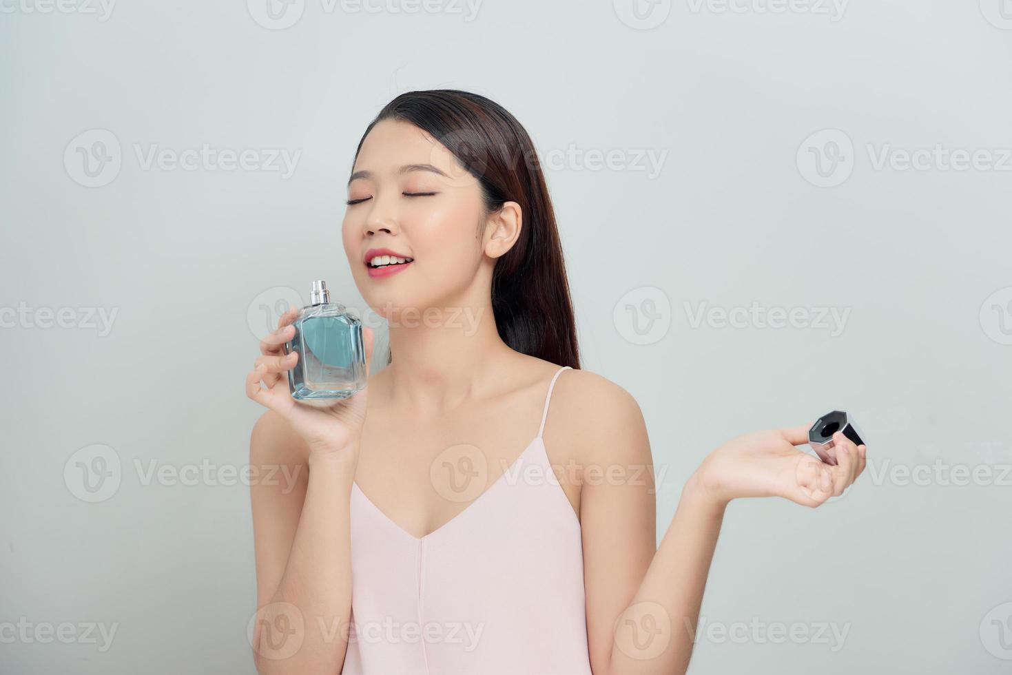 Beautiful young woman smelling her perfume photo