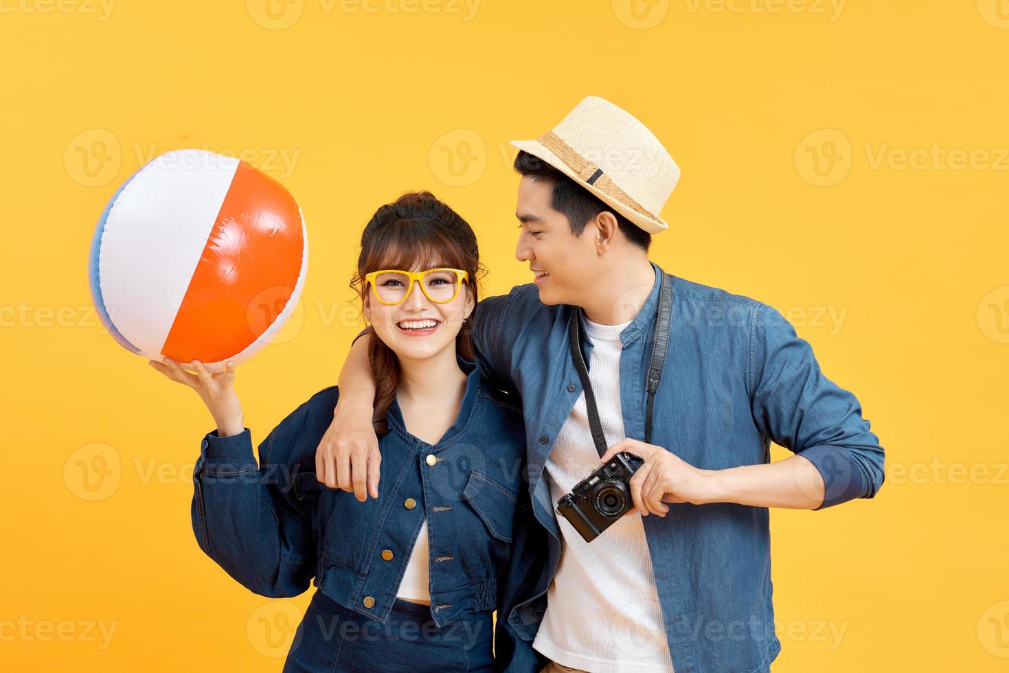 Lovely Asian couple in summer casual clothes with beach accessories isolated on colorful yellow banner background with copy space photo
