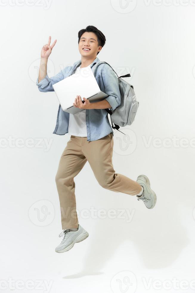 Happy jumping Asian programmer with laptop on color background photo