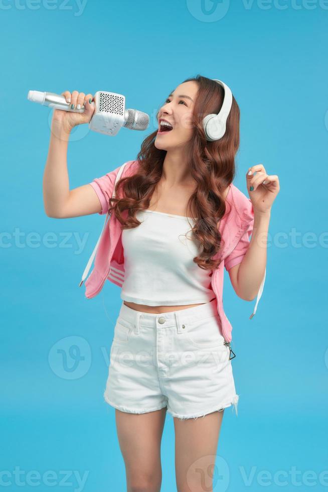 Young happy and beautiful Asian girl singing karaoke song excited, cheerful emulating pop music star photo