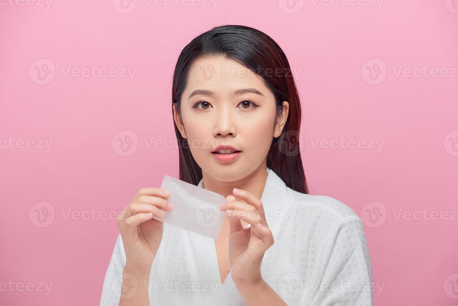 Young asian skin care woman smile and use oil blotting paper on her face photo