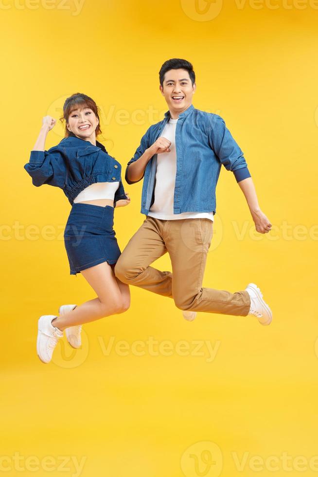 Full length body size view of nice attractive lovely cheerful cheery couple jumping up in air isolated over yellow background photo