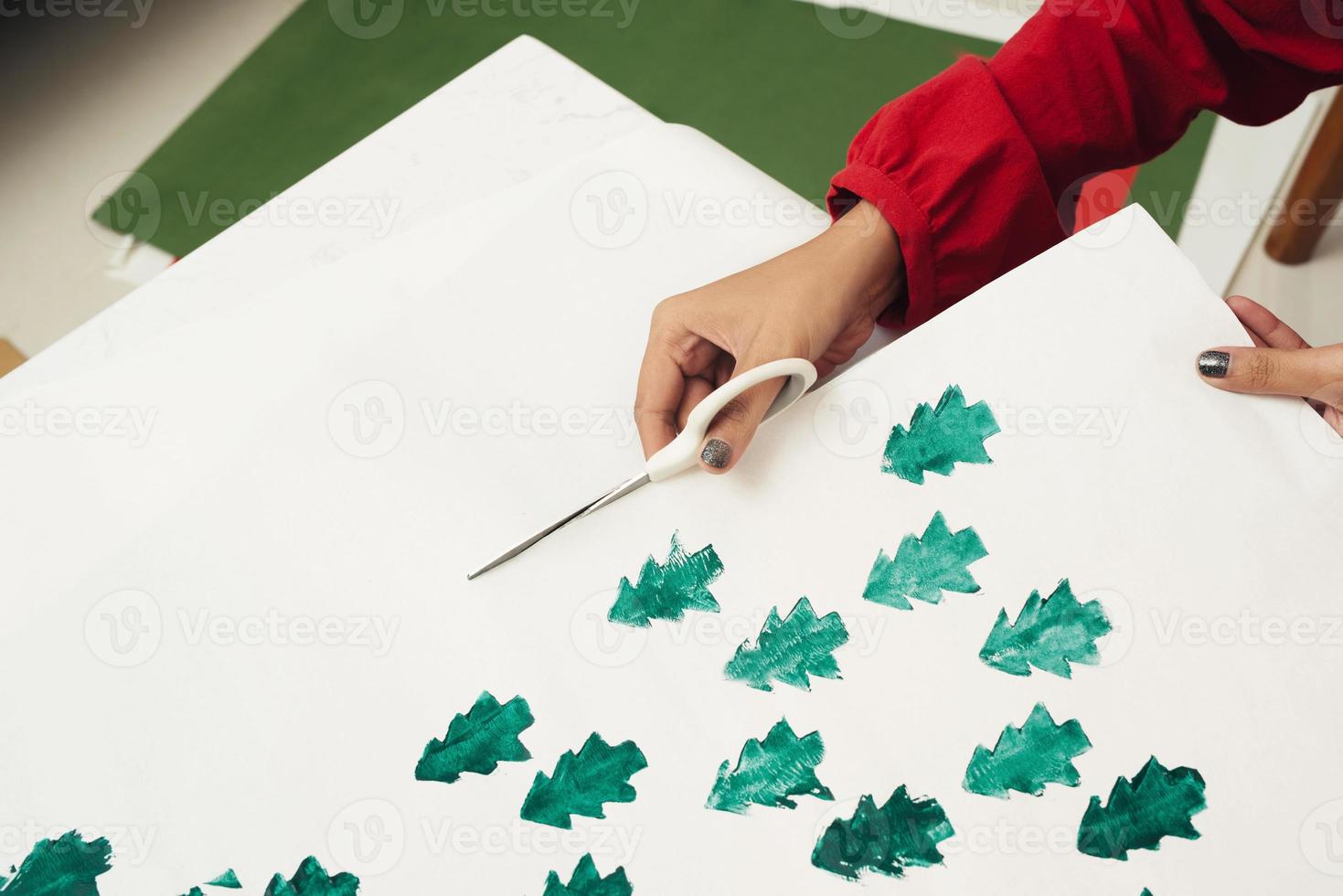 Woman cutting kraft paper and making envelopes at workshop, studio. Handmade and Xmas concept photo