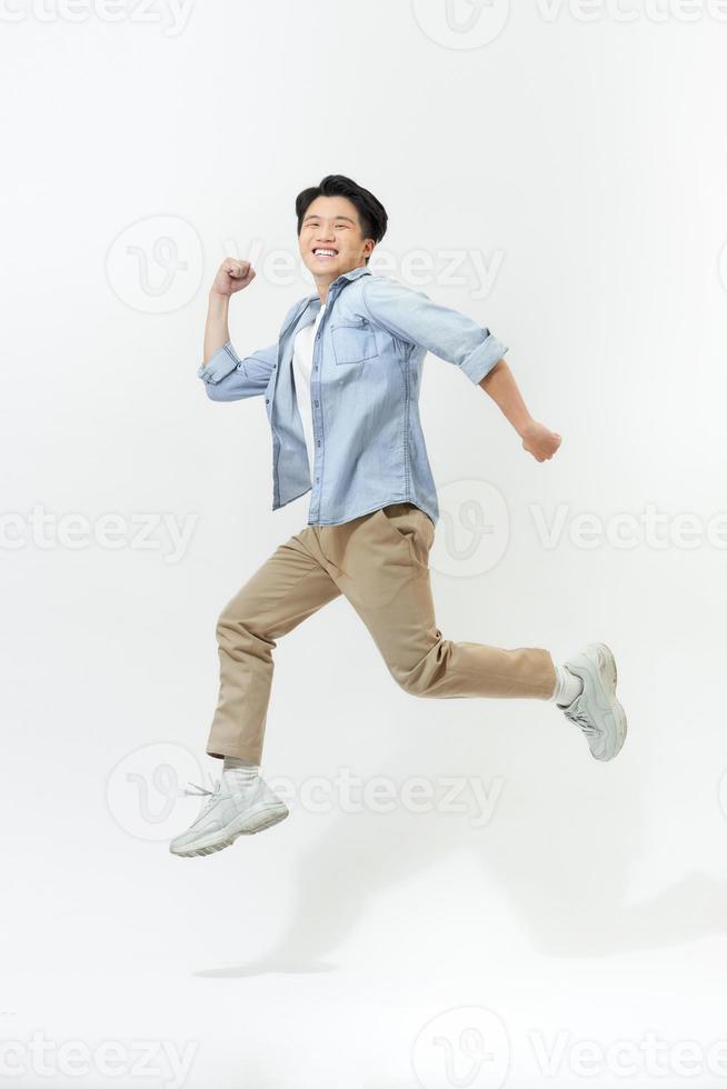 Atractivo chico alegre saltando corriendo aislado sobre fondo blanco. foto