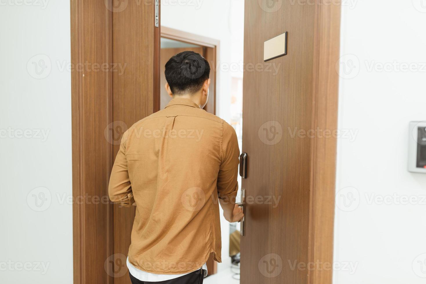 hombre que vuelve a casa del trabajo y abre la puerta del apartamento foto