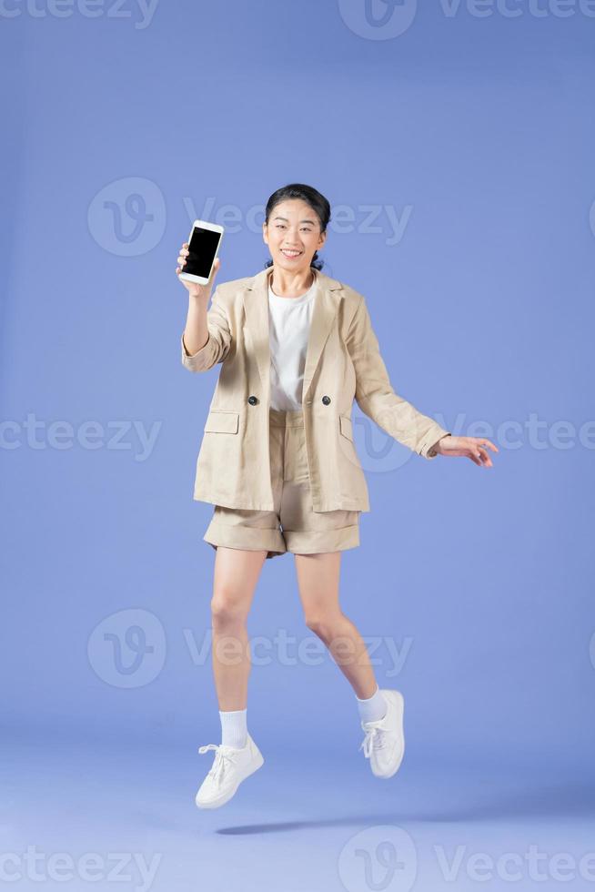 Happy young woman flying and jumping in air and showing big mobile empty screen for copy space and advertising area photo