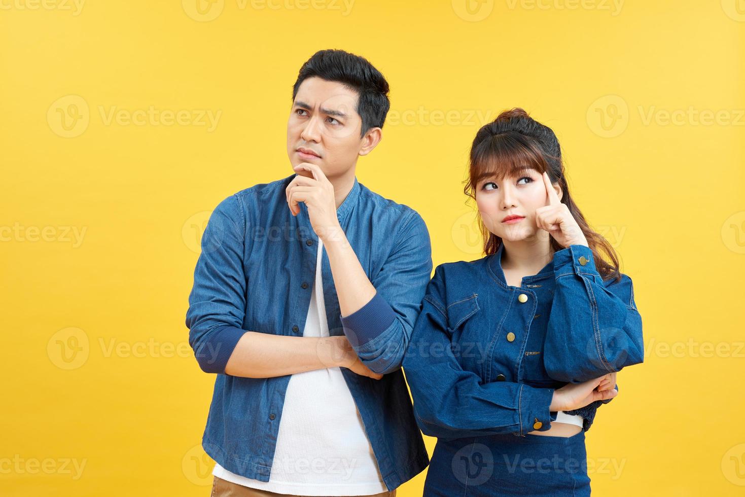 Image of serious man and woman in casual wear touching chins and looking aside isolated over colorful background photo