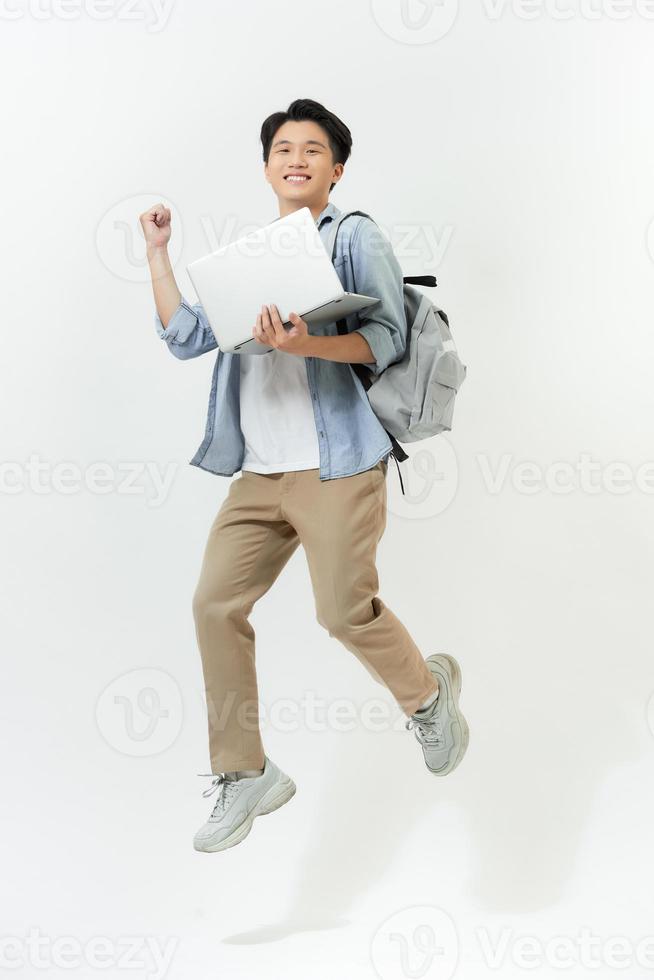 Jumping male Asian programmer with laptop on white background photo