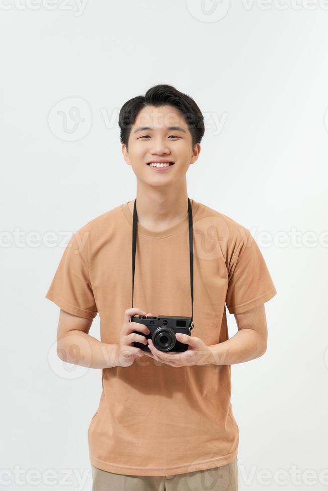 Confident photographer. Handsome young man holding digital camera and smiling while standing against white background photo