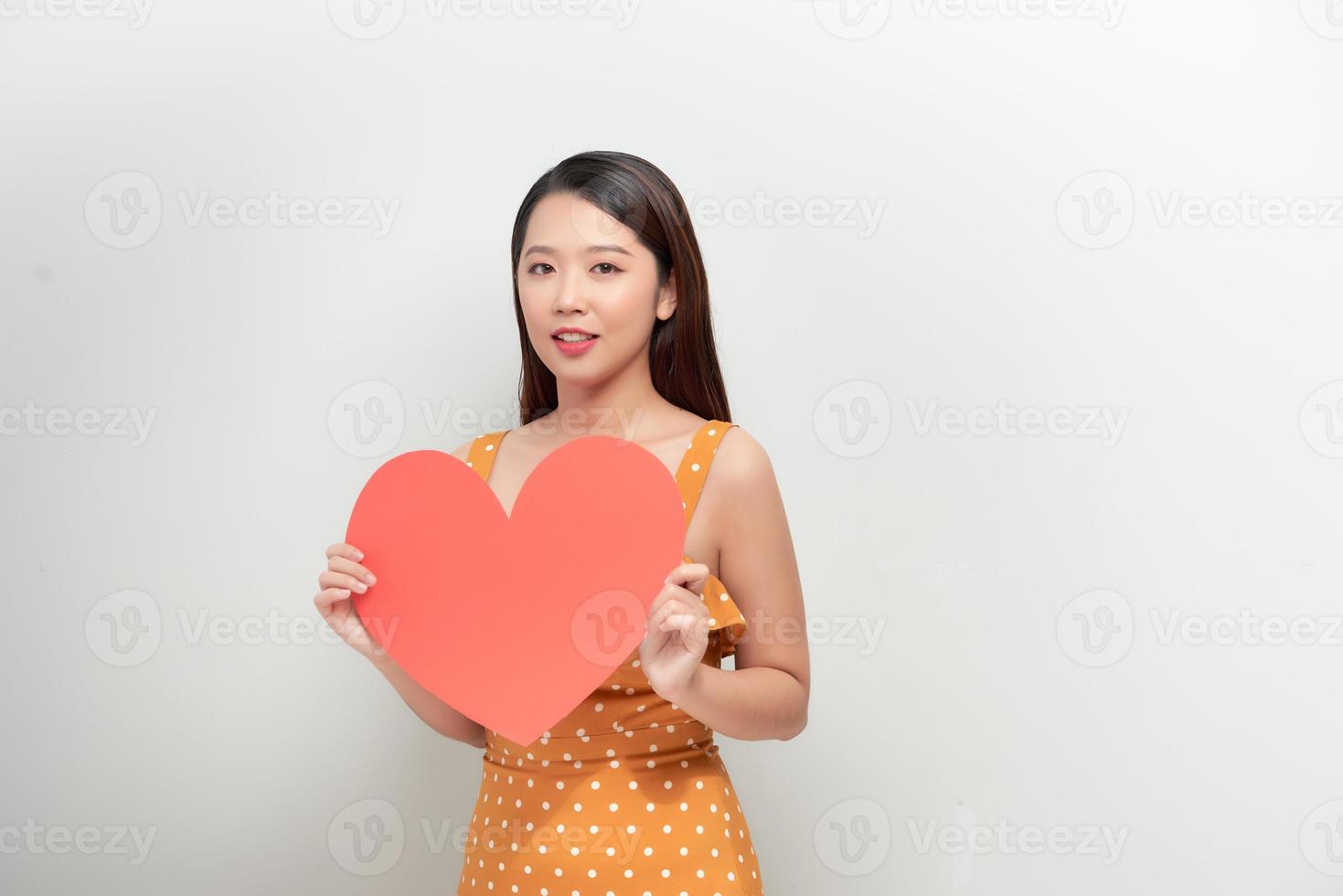 Lifestyle and Holiday Concept - Portrait Young happy woman in polka dot dress holding big red heart paper. photo
