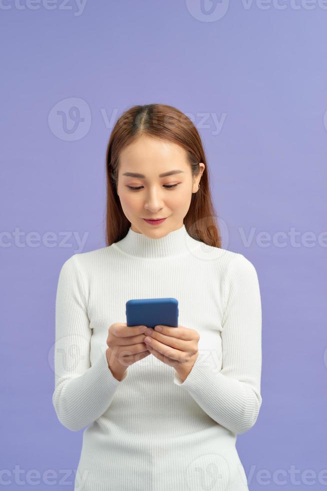 attractive asian woman using smart phone isolated on violet background photo